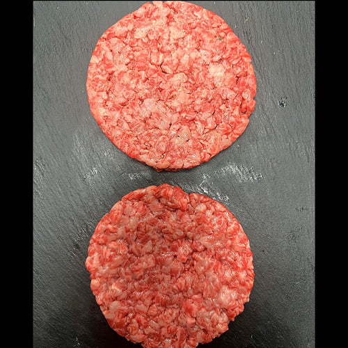 Two raw hamburger patties on a dark surface